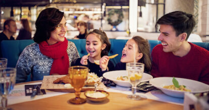 Family of four eating at a restaurant during the holidays.