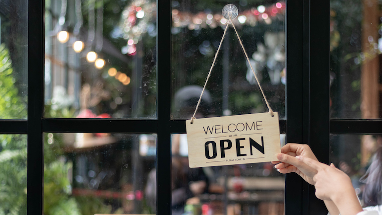 Wooden open sign in front of glass window of a restaurant.