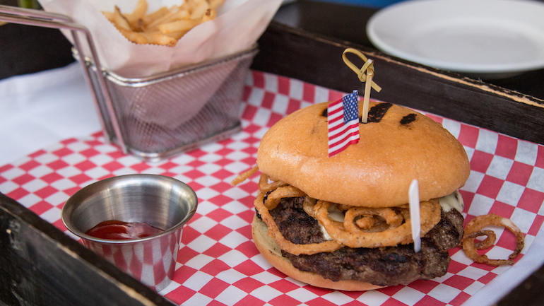 Steak burger with french fries and ketchup on a tray.