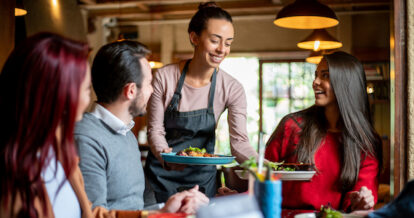 Restaurant server serving a table their food.