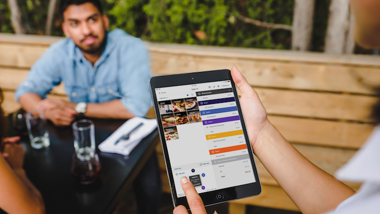 Restaurant sever using a mobile tablet to take a table's order.