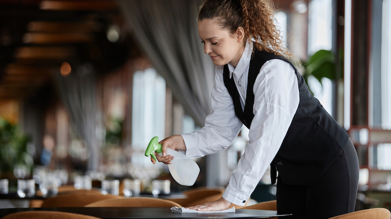 Restaurant busser cleaning a table.