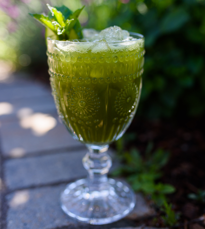 A close up of a matcha mint garden and tonic, a recipe from Colorado's Yampa Valley Kitchen in a glass displayed outside.