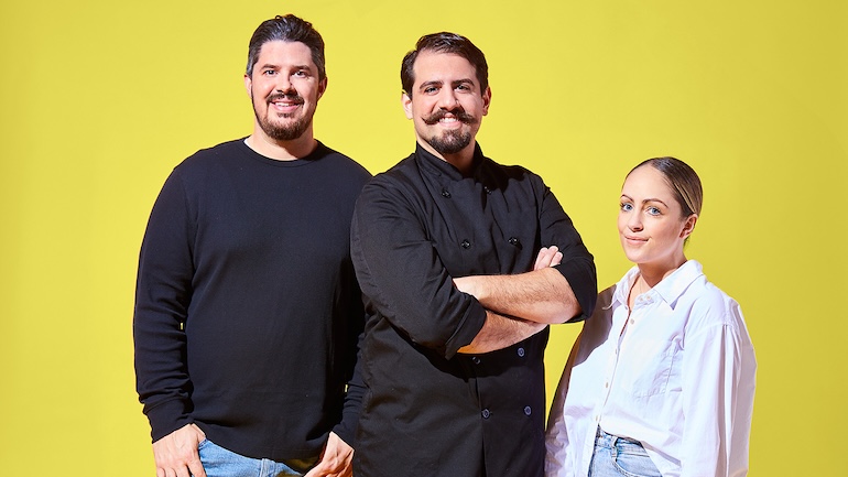 A group photo of three people in front of plain yellow background.