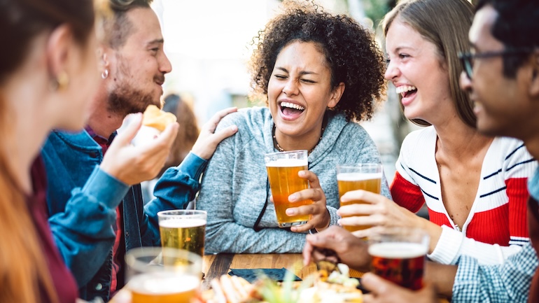 Group of 5 friends at a restaurant patio enjoying a few beers and food.