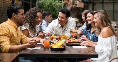 A group of five friends sitting at a table at a restaurant enjoying a meal together.