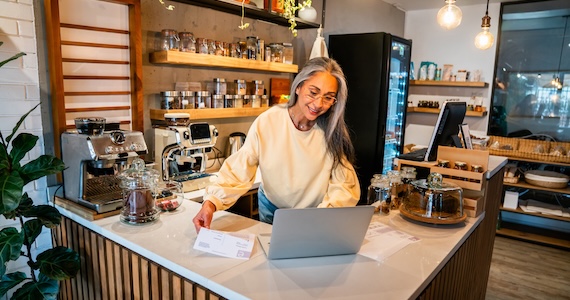 A business owner doing back of house work on her laptop at her coffee shop.