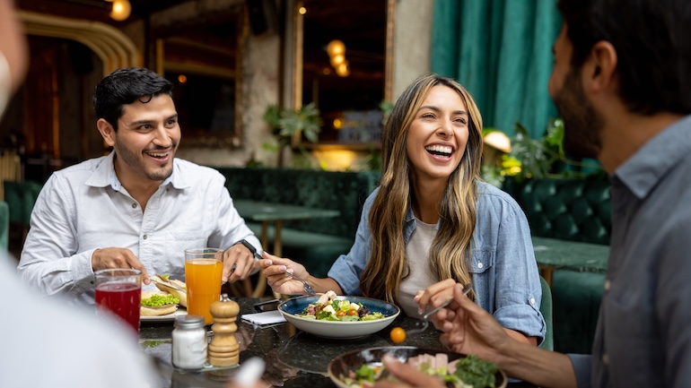 Group of friends eating at a restaurant and laughing.