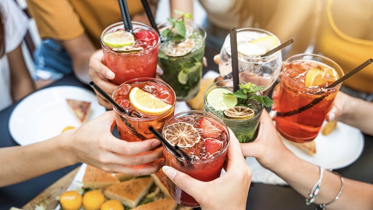 Group of people toasting drinks while sitting at a table at a restaurant.