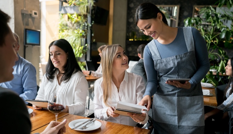 Server taking a tables order at a restaurant.